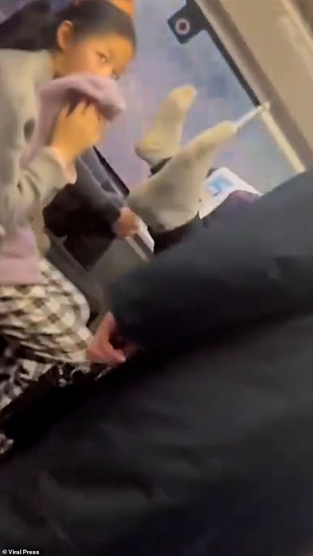 The exasperated local can be seen covering her face with a towel before two train workers intervene